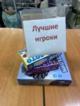 На фотографии изображена стопка из трёх настольных игр: 1. Лото (с пластмассовыми фишками). 2. MEMO «Мир животных». 3. «Властелин слов».,на которой закреплен белый лист бумаги с надписью «Лучшие игроки».